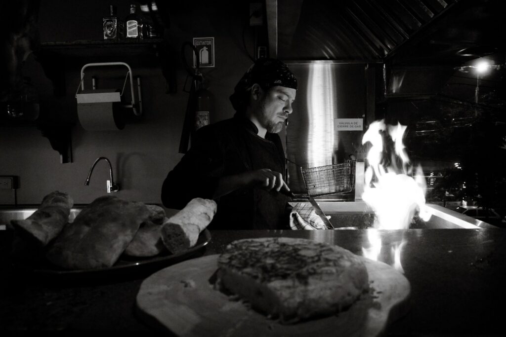 Chef cooking over an open flame in a restaurant kitchen